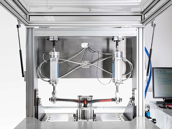 Ein Teststand für Fahrradlenker zeigt hydraulische Zylinder, die eine Lenkerstange in Bewegung setzen.